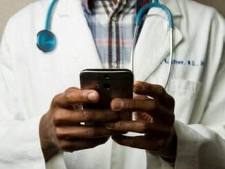 Doctor on a smartphone illustrating the AI Airlock scheme from the Medicines and Healthcare products Regulatory Agency (MHRA) in the UK that aims to accelerate the adoption of artificial intelligence technologies into the NHS healthcare system with a high emphasis on safety.