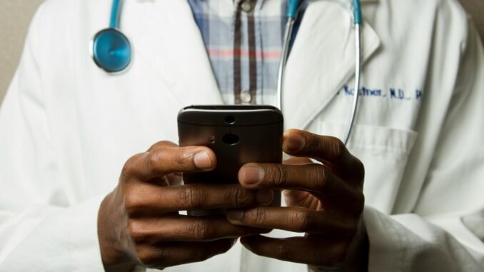 Doctor on a smartphone illustrating the AI Airlock scheme from the Medicines and Healthcare products Regulatory Agency (MHRA) in the UK that aims to accelerate the adoption of artificial intelligence technologies into the NHS healthcare system with a high emphasis on safety.